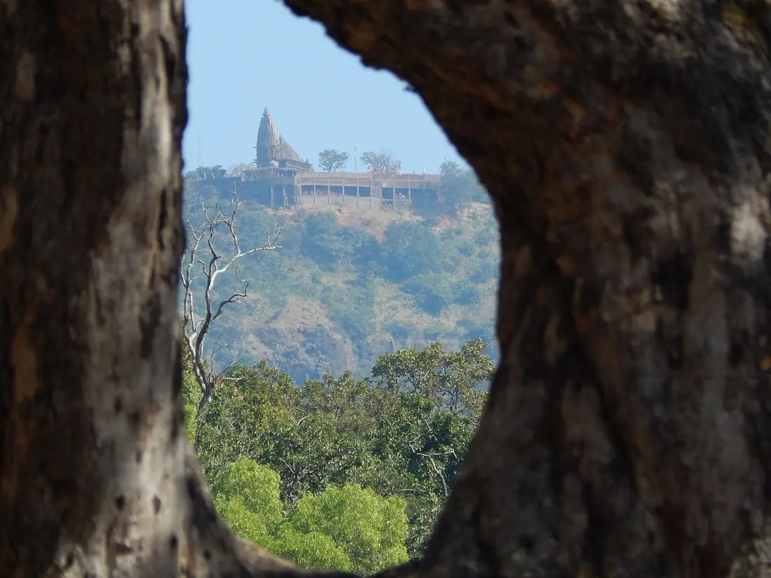 Distant Chauragarh hilltop temple framed by a rock opening.